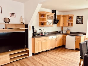 A modern kitchen with wooden cabinets, a built-in oven, a coffee maker, and a dishwasher.