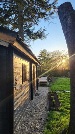 A wooden cabin with a gravel path leading to a wooden deck, surrounded by trees and a grassy area. - Cosy cabin on the banks of the Thérain - calm and nature (Herchies)