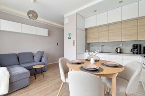 Uma sala de estar moderna com sofá, mesa de jantar com cadeiras e cozinha com armários e eletrodomésticos.