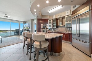 Una cocina moderna con una isla grande, electrodomésticos de acero inoxidable y vistas al exterior.