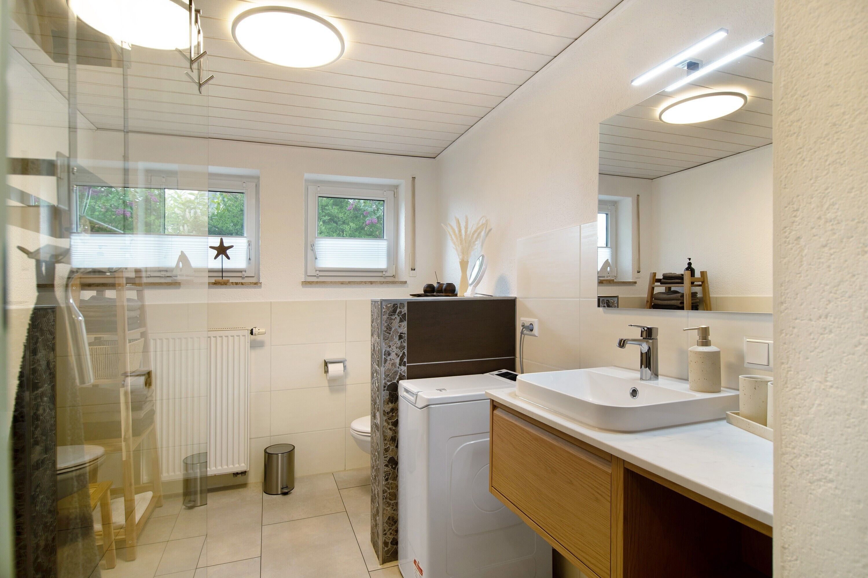 Un bagno moderno con un lavandino bianco, uno specchio e una finestra decorata con stelle.
