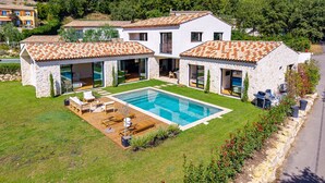 Ein modernes, zweistöckiges Haus mit Swimmingpool, Steinmauern und einem Ziegeldach.