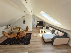 Ein modernes Loft mit Essbereich, einer Sofagarnitur, einem Fernseher und einem großen Fenster.