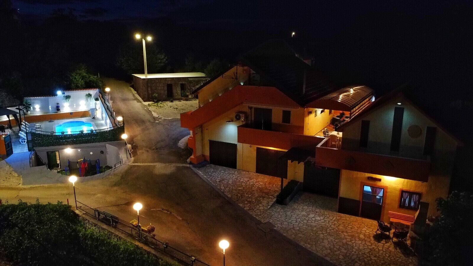 A hotel with a swimming pool, a covered outdoor area, and a stone-paved courtyard.