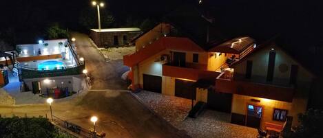 A hotel with a swimming pool, a covered outdoor area, and a stone-paved courtyard.