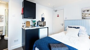Une chambre d’hôtel équipée d’un lit, d’un bureau avec une machine à café, d’un four à micro-ondes et d’une télévision.