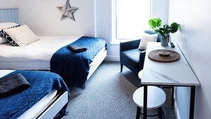 Une chambre à coucher avec un lit, un bureau, une chaise, une fenêtre et deux étoiles décoratives sur le mur.