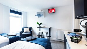 Une chambre d’hôtel avec deux lits, un bureau, une chaise, une télévision et une fenêtre.