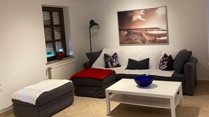 Ein Wohnzimmer mit Sofa, Hocker, Couchtisch und einem Bild an der Wand.