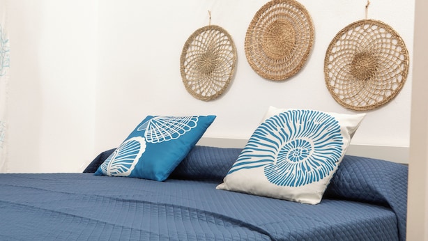 A bed with a blue quilted bedspread and two pillows with blue and white patterns. - Casa Mara - 10 minutes from the beach (Porto Pozzo)