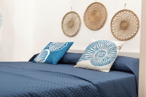 A bed with a blue quilted bedspread and two pillows with blue and white patterns. - Casa Mara - 10 minutes from the beach (Porto Pozzo)