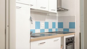 A modern kitchen with white cabinets, a stainless steel range hood, a blue and white tiled backsplash, and a built-in oven. - Casa Mara - 10 minutes from the beach (Porto Pozzo)