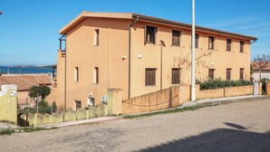A two-story building with a flat roof, multiple windows, and a visible streetlight. - Casa Mara - 10 minutes from the beach (Porto Pozzo)