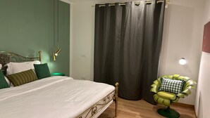 A bedroom with a bed, a green chair, a curtain, and a wall-mounted light. - Villa Elisa - Ottavia Apartment near Venice with garden and parking (Spinea)