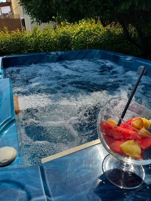 A hot tub with a glass bowl of fruit on the edge.
