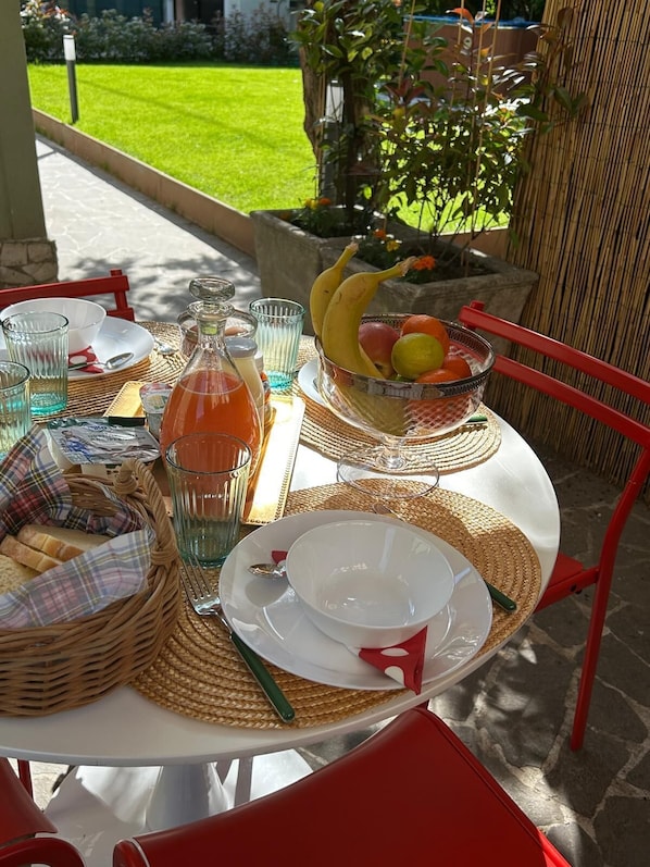 Un espace de restauration en plein air avec une table, des chaises et un saladier rempli de fruits.