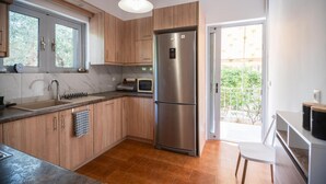 Cozinha moderna com armários de madeira, geladeira de aço inoxidável, pia e janela.