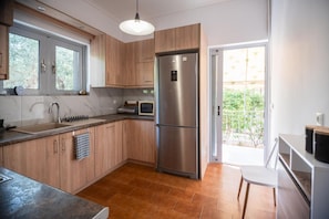 A modern kitchen with wooden cabinets, a stainless steel refrigerator, a sink, and a window. - Ruby’s House Apartment with Balcony, Wi-Fi and Air Conditioning (Glifada)