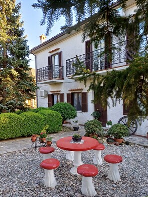 A building with a balcony, potted plants, and a round table with stools.