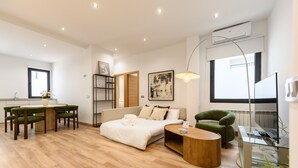 A modern living room with a sofa, a dining table with chairs, a coffee table, and a TV. - (DDS1014) 2 bedroom apartment in Goya, Salamanca District (Madrid)