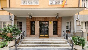 A building entrance with a brick facade, a black door, and a set of stone steps leading up to a covered area. - (DDS1014) 2 bedroom apartment in Goya, Salamanca District (Madrid)