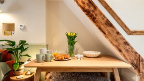 A breakfast setup with croissants, a vase of yellow flowers, and a coffee pot on a wooden table in a room with a sloped ceiling. - Beautiful One Bedroom Home in Glastonbury (Glastonbury)
