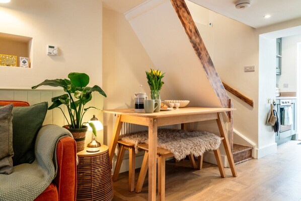 A cozy living room with a wooden table, a plant, and a small lamp.