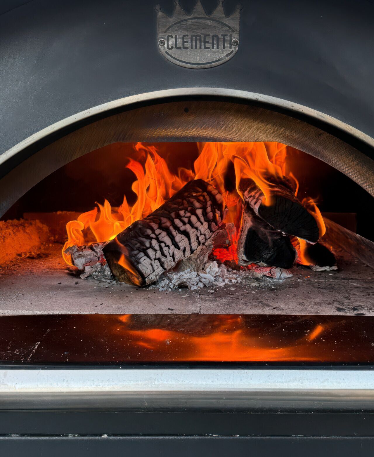 A wood-fired oven with visible flames and a logo that reads 'Clementi.'