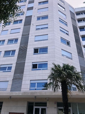 A multi-story building with a modern architectural design, featuring a series of windows and a palm tree in the foreground. - Areeiro Elegant by Homing (Lisbon)