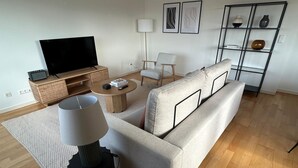 Ein modernes Wohnzimmer mit einer Couch, einem Couchtisch, einem Fernseher und einem Bücherregal.