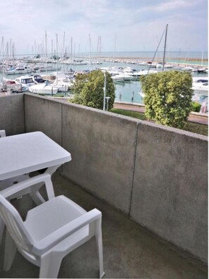 Ein Balkon mit Tisch und Stühlen mit Blick auf einen Yachthafen und Boote.