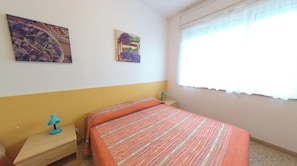 Ein Schlafzimmer mit einem Bett, einem Nachttisch, einer Lampe und zwei an der Wand hängenden Bildern.