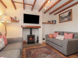 Ein Wohnzimmer mit Kamin, Sofas, einem Fernseher und einem gemusterten Teppich.