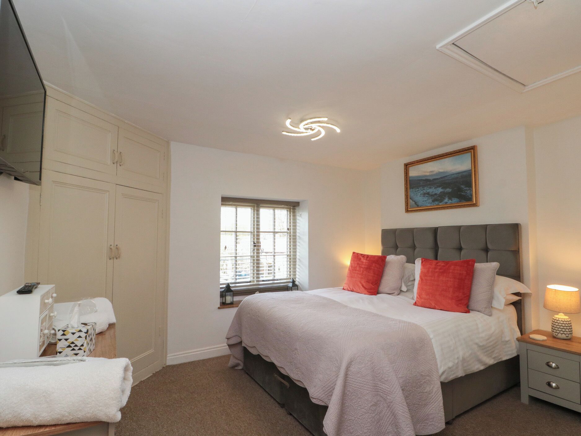 A bedroom with a bed, a nightstand, a window, and a wardrobe.