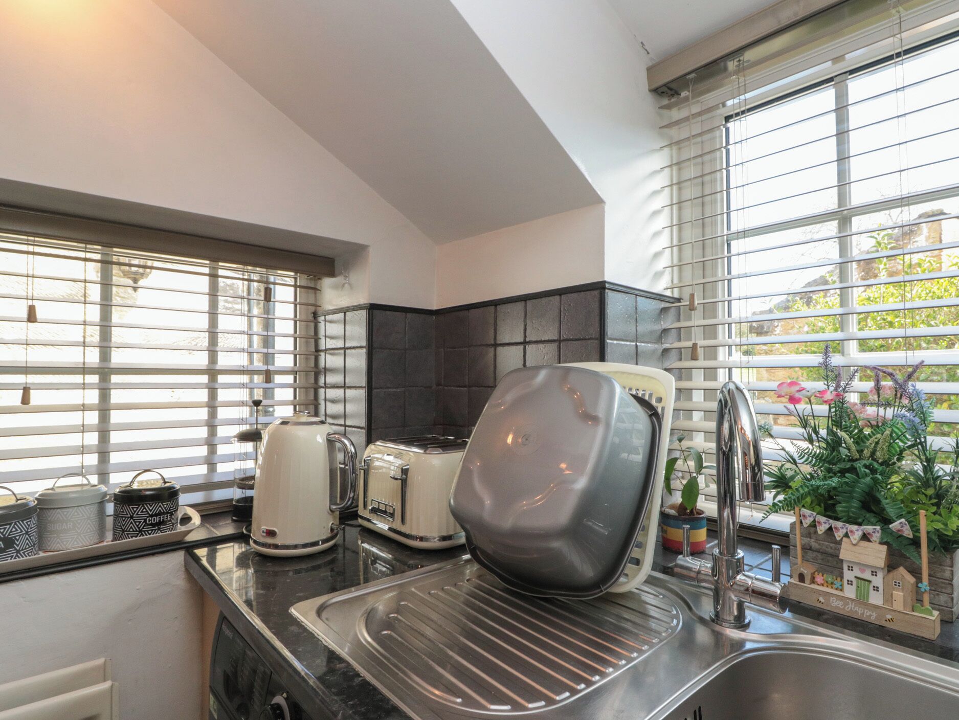 A kitchen with a sink, a toaster, a kettle, and a coffee maker.