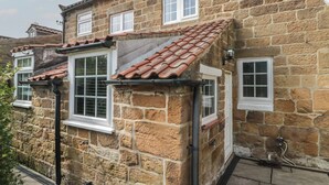 A stone building with a tiled roof, multiple windows, and a visible chimney. - Isla Cottage (Northallerton)