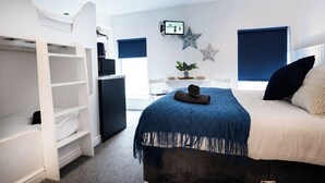 Een slaapkamer met een bed, een bureau, een stoel, een televisie en een kledingkast.