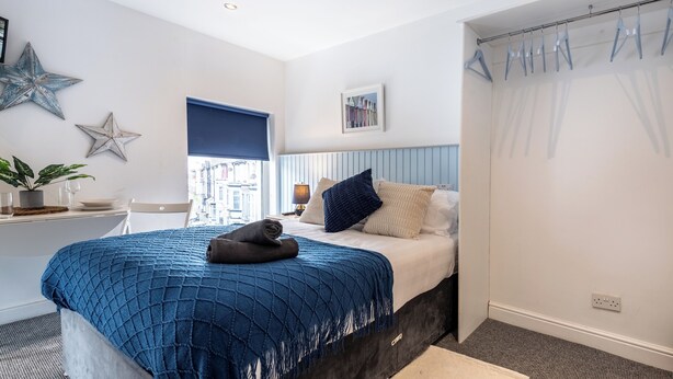 Een slaapkamer met een bed, nachtkastje, raam met uitzicht en een sterren decoratie aan de muur.