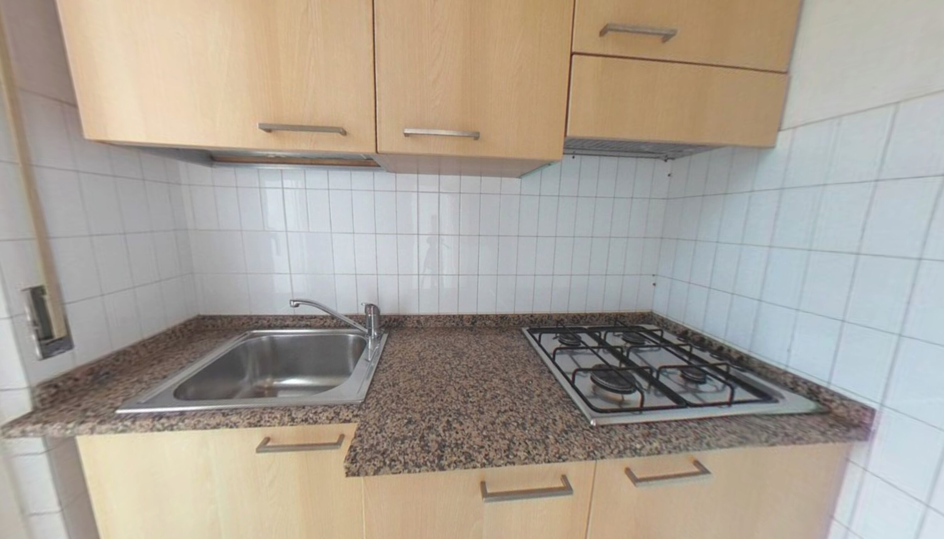 Cocina con encimera de granito, pileta de acero inoxidable y cocina a gas.