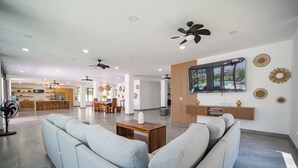 Amplia sala de estar con un sofá, una mesa de centro y un televisor montado en la pared.