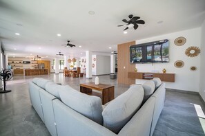 A spacious living area with a sofa, a coffee table, and a TV mounted on the wall.