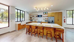 Una cocina moderna con una isla grande, armarios de madera y televisor integrado.