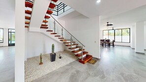 A spacious interior with a modern staircase, a dining area, and large windows. - Beachfront Private Villa+pool+Gazebo+BBQ+6Bedrooms+7Bathrooms (Playa san marcelino)