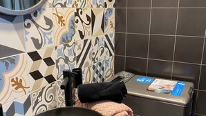 Un baño con un lavabo negro, una toalla y una lavadora.