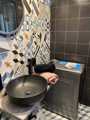 A bathroom with a black sink, a towel, and a washing machine. - Wyn-cozy Studiostniarchos Foundation Near the Sea (Kallithea)