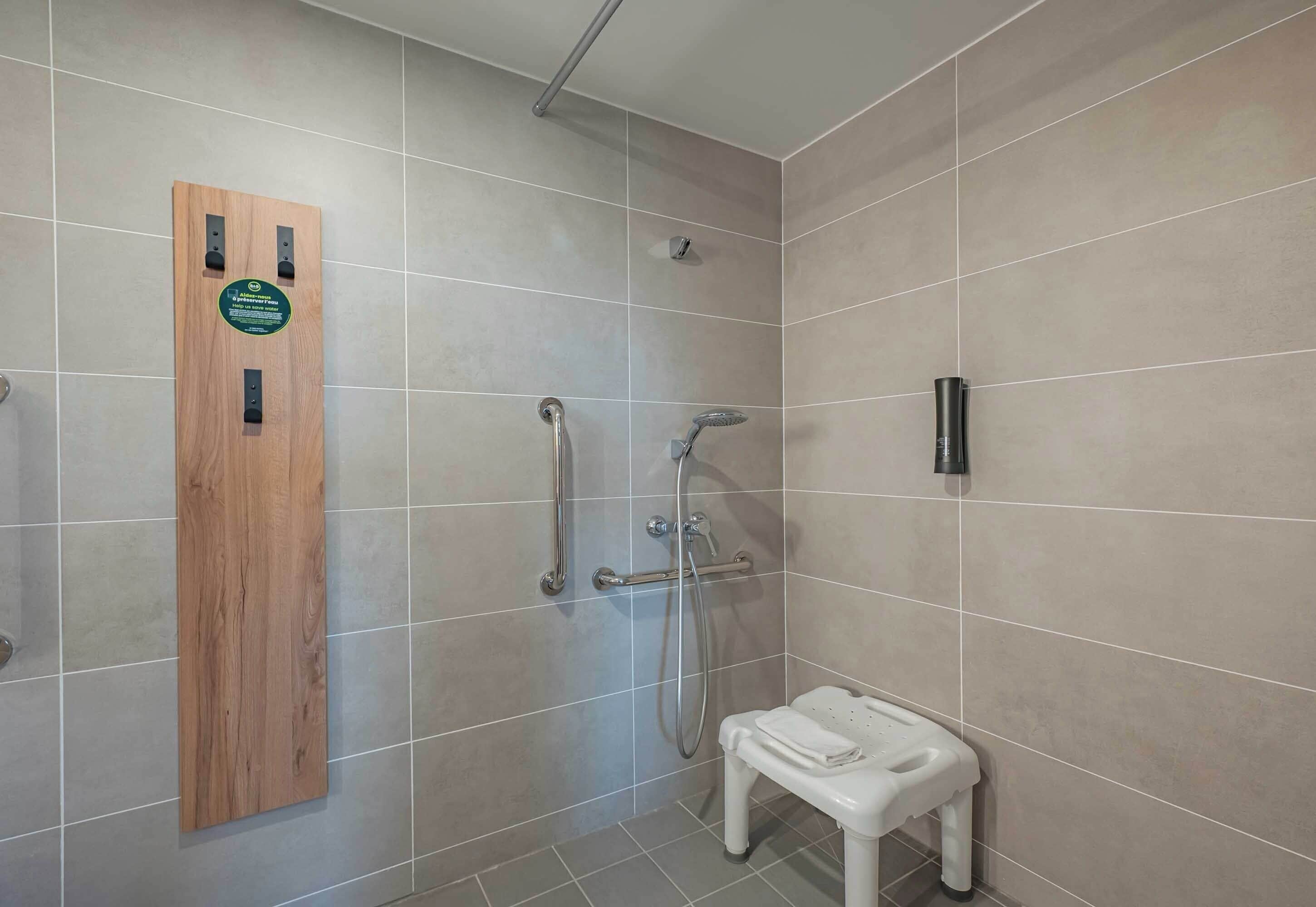 A shower area with a wooden panel, a handheld showerhead, a handheld shower, and a small white stool.