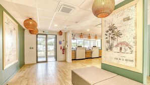 A hotel lobby with a wooden floor, a reception desk, and a wall-mounted map. - B&B Hotel La Réunion Aéroport (Sainte Marie)