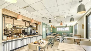 A café with a counter, seating area, and a view of the street. - B&B Hotel La Réunion Aéroport (Sainte Marie)