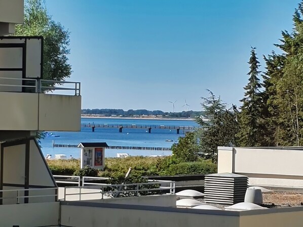 A view of a river with a bridge, wind turbines, and a small kiosk. - Stylish vacation apartment Seeluft in Großenbrode. Balcony with wonderful sea view. Family-friendly furnishings and maximum sleeping comfort in a box-spring bed. Practical washing machine and iron (Großenbrode)