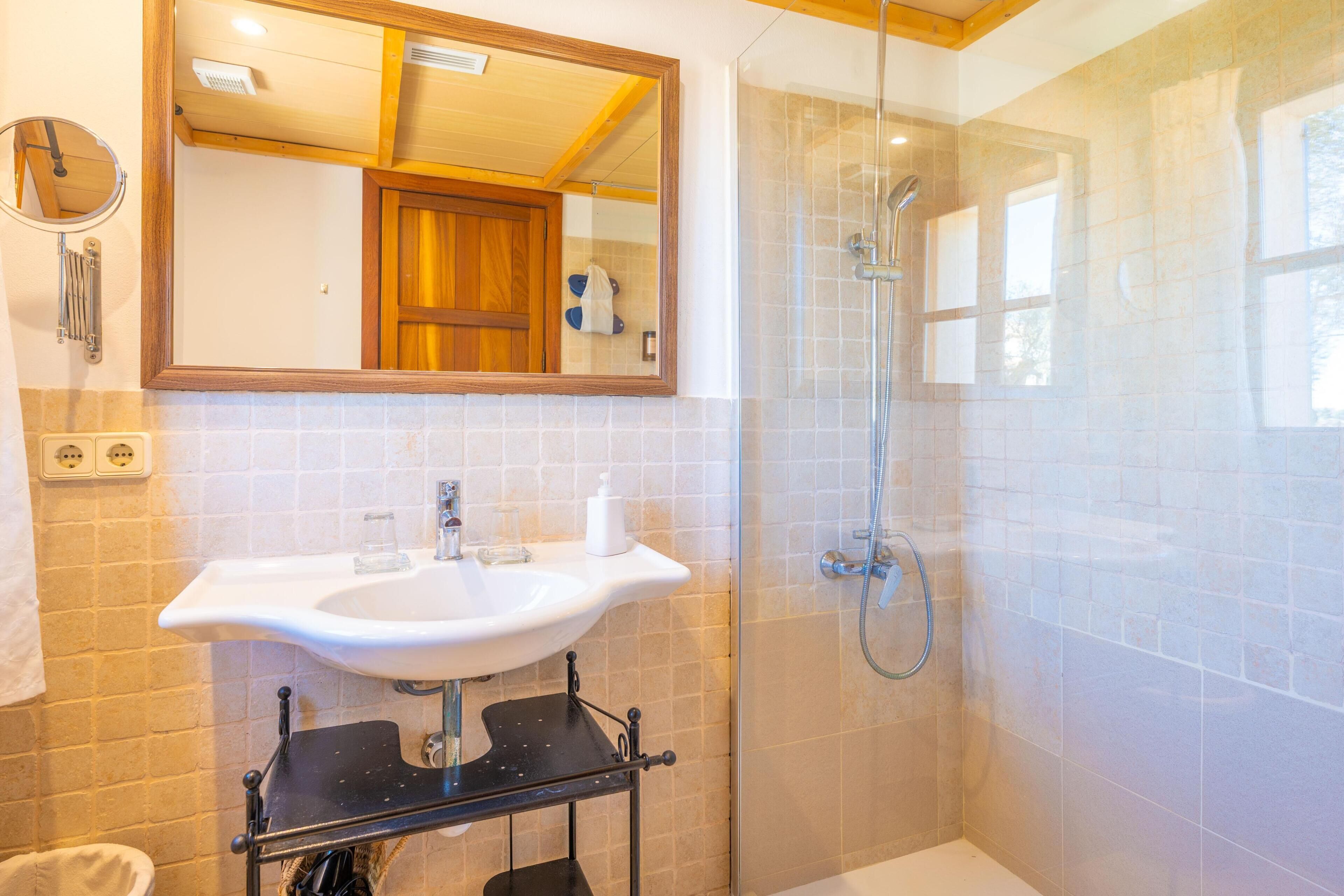A bathroom with a white sink, a mirror, and a glass-enclosed shower.